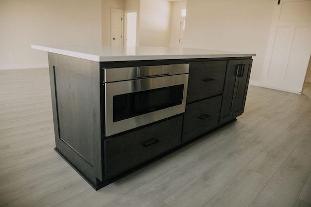 interior details with a kitchen island and light wood-type flooring