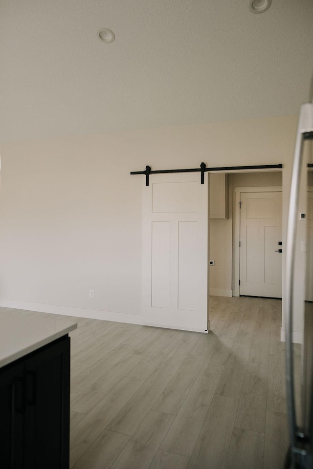 empty room with a barn door and light hardwood / wood-style floors