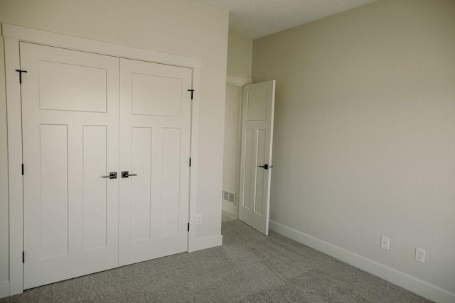 unfurnished bedroom featuring light colored carpet and a closet