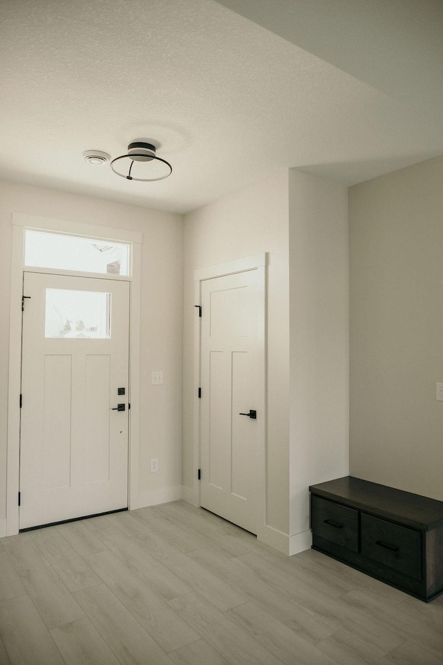 foyer with light wood-type flooring and a textured ceiling