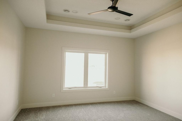 carpeted empty room with a tray ceiling and ceiling fan