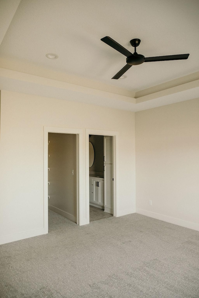 carpeted empty room featuring a raised ceiling and ceiling fan