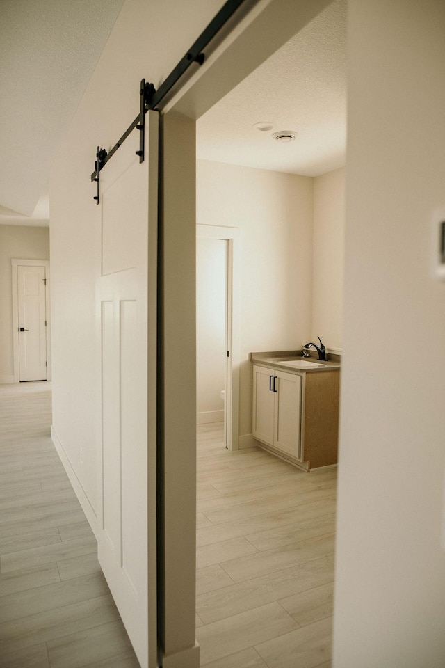 hallway featuring a barn door and light hardwood / wood-style flooring