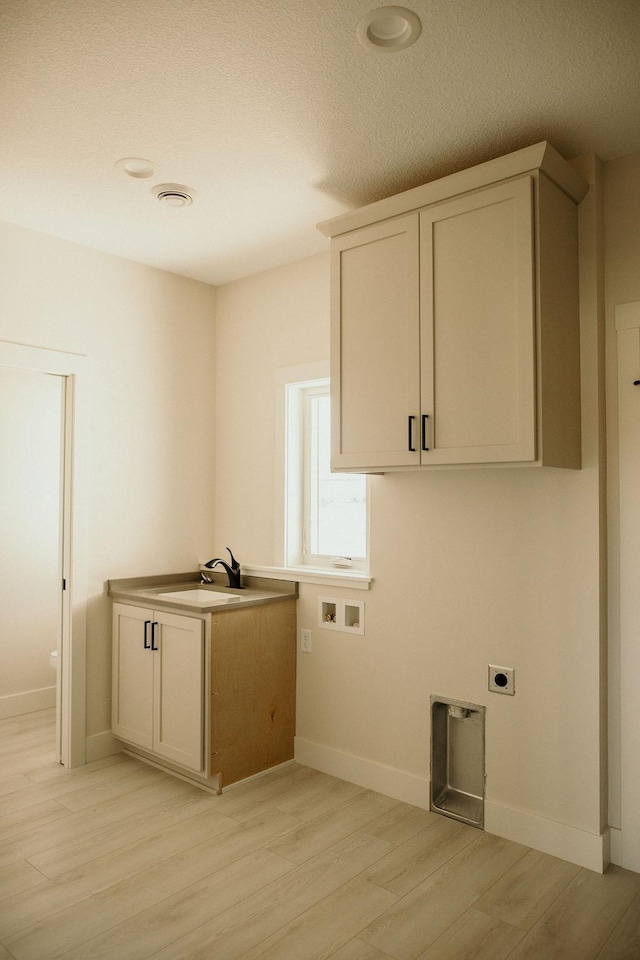 laundry area featuring sink, cabinets, hookup for an electric dryer, hookup for a washing machine, and light wood-type flooring