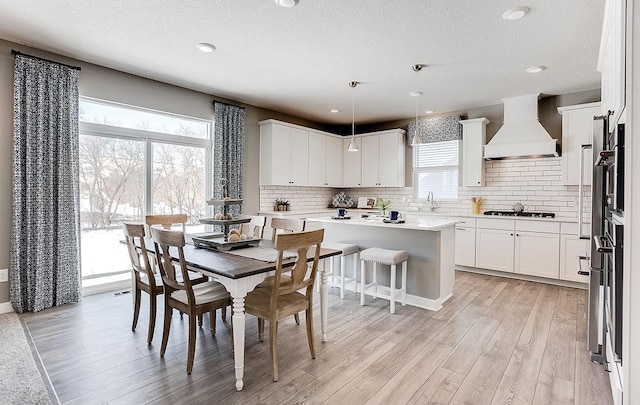 dining area with light hardwood / wood-style floors, a textured ceiling, and sink