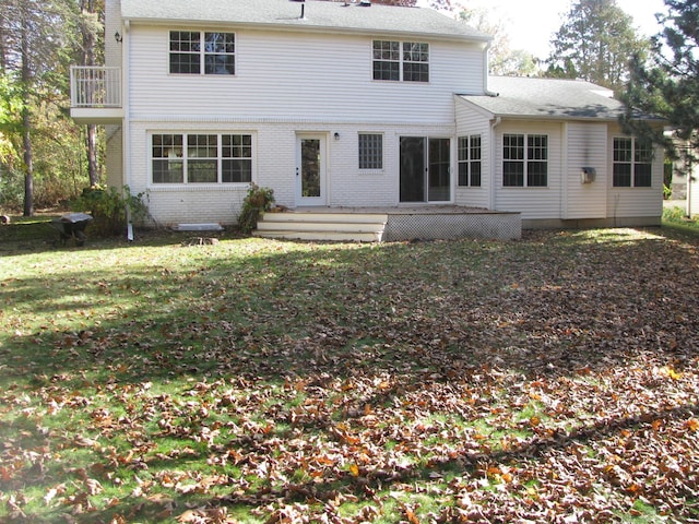 back of property with a deck and a lawn