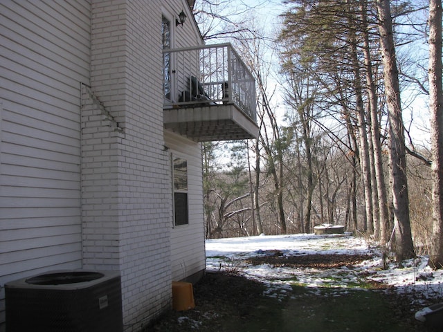 view of snow covered exterior with a balcony and central AC unit