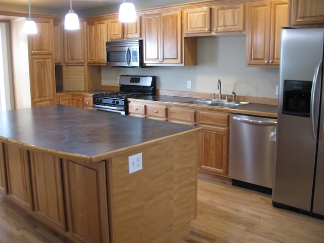 kitchen with sink, stainless steel appliances, hanging light fixtures, and light hardwood / wood-style flooring