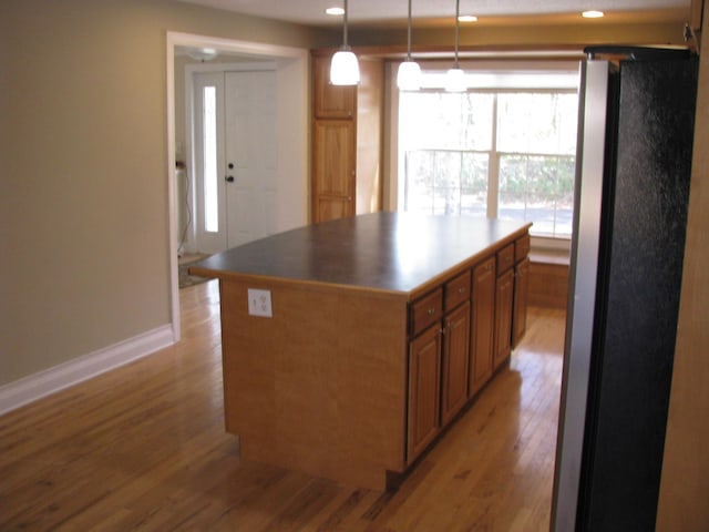 kitchen featuring a center island, decorative light fixtures, stainless steel fridge, and light wood-type flooring