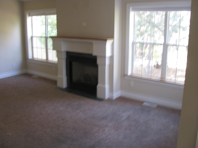 unfurnished living room featuring carpet flooring and a healthy amount of sunlight