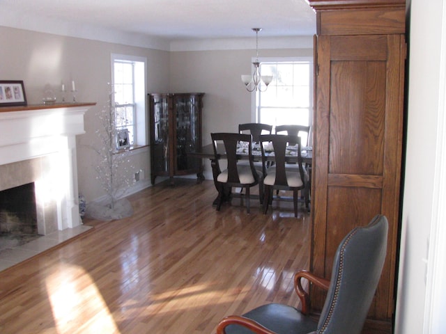 dining area with a tile fireplace, dark hardwood / wood-style floors, an inviting chandelier, and plenty of natural light