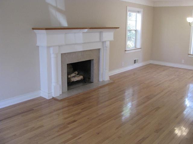 unfurnished living room featuring light wood-type flooring and a tiled fireplace