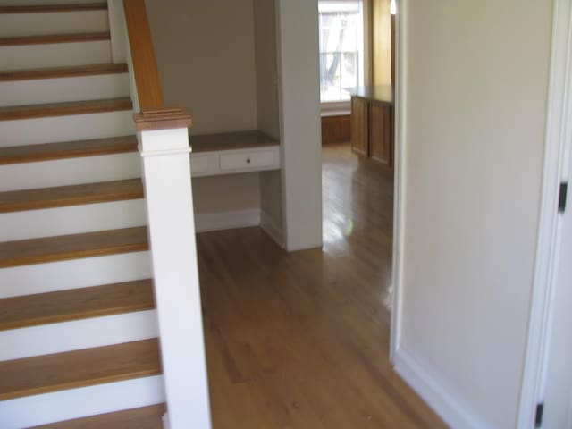 stairs featuring built in desk and wood-type flooring