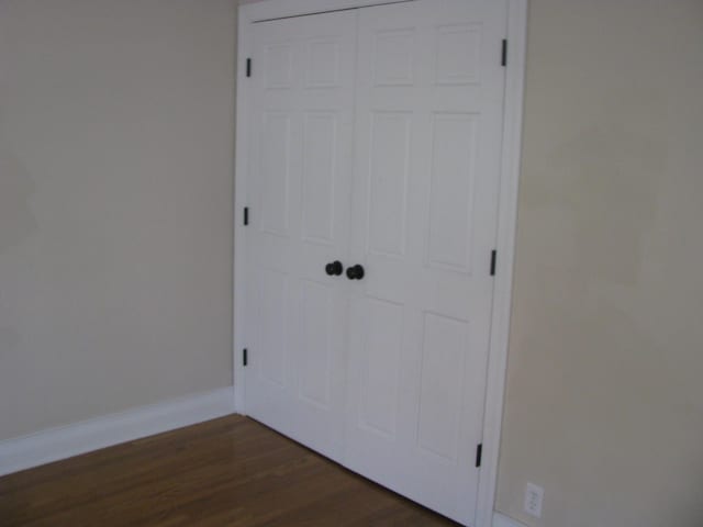 unfurnished bedroom with dark wood-type flooring and a closet