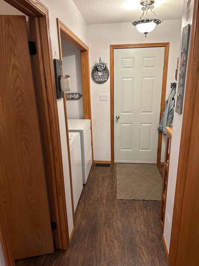 hallway featuring washer and clothes dryer, a textured ceiling, and dark hardwood / wood-style flooring