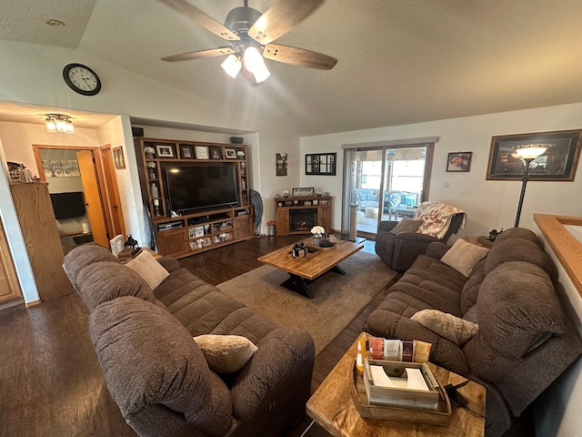 living room with a fireplace, a textured ceiling, dark hardwood / wood-style floors, vaulted ceiling, and ceiling fan