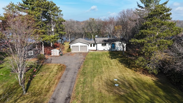 view of front of property featuring a garage, a shed, and a front lawn