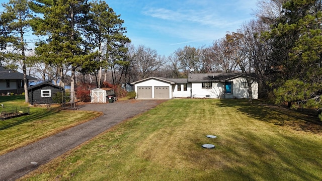 ranch-style house with a storage unit, a front yard, and a garage