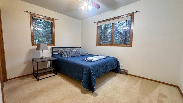 bedroom with light colored carpet, ceiling fan, and a baseboard heating unit