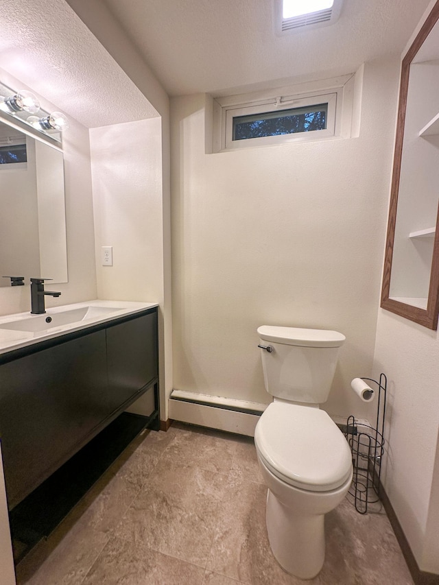 bathroom featuring vanity, a textured ceiling, toilet, and a baseboard heating unit