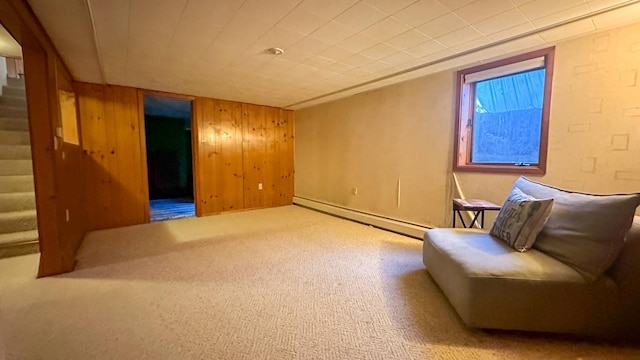 living area with a baseboard radiator, carpet flooring, and wooden walls