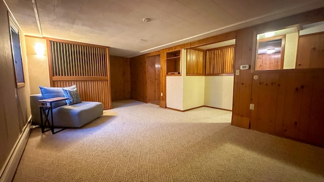 sitting room with wooden walls, carpet flooring, and a baseboard radiator