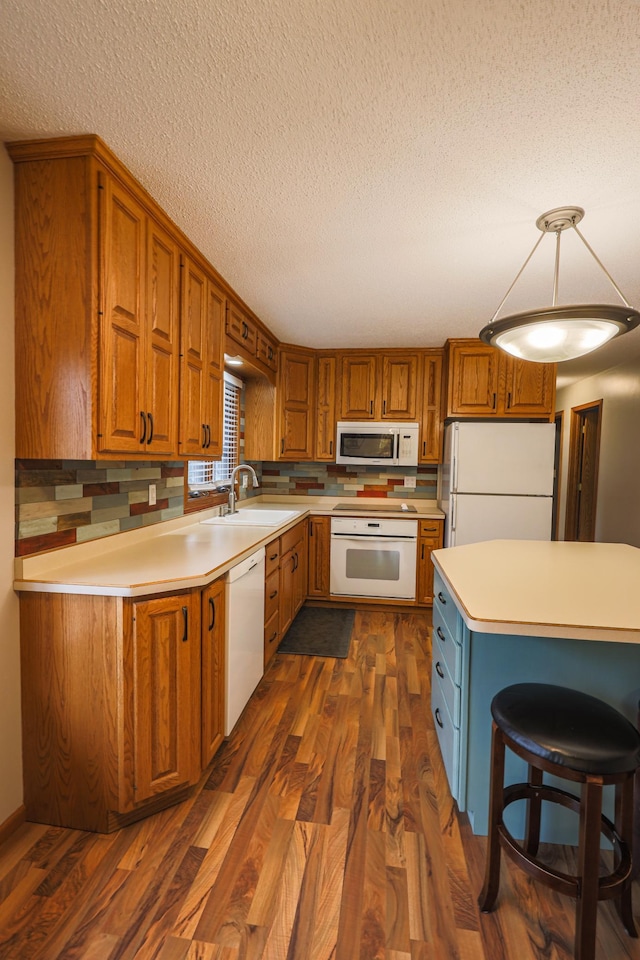 kitchen with dark hardwood / wood-style flooring, white appliances, a textured ceiling, and sink