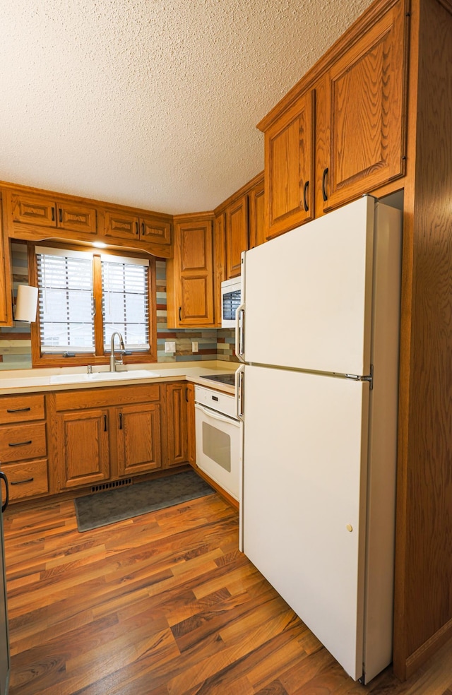 kitchen featuring white appliances, sink, a textured ceiling, tasteful backsplash, and dark hardwood / wood-style flooring