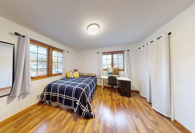 bedroom featuring light hardwood / wood-style floors and a textured ceiling