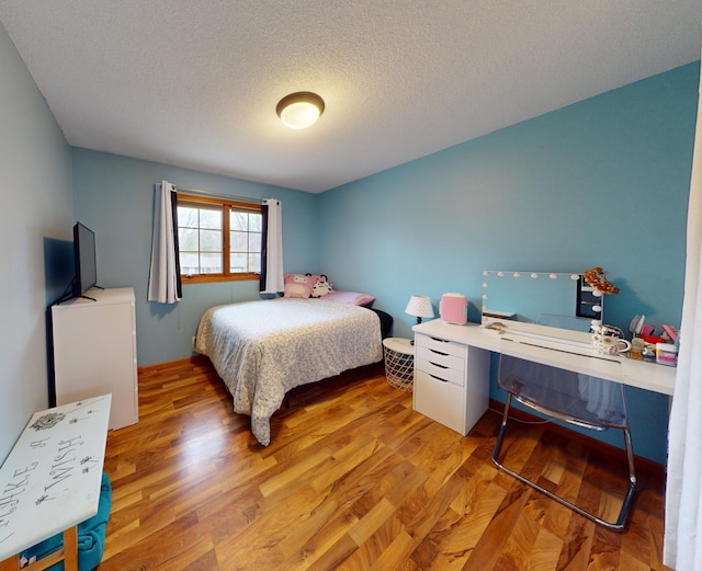 bedroom with light wood-type flooring and a textured ceiling