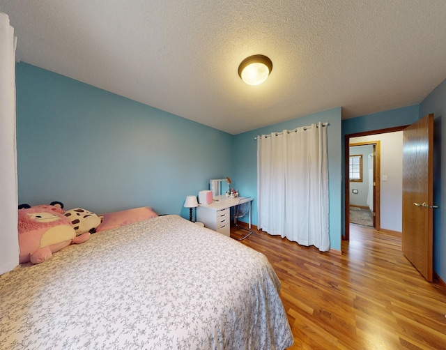 bedroom featuring a textured ceiling and light hardwood / wood-style flooring