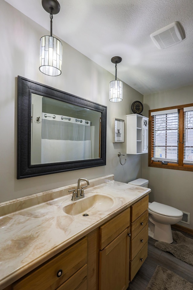 bathroom featuring a shower with shower curtain, vanity, a textured ceiling, wood-type flooring, and toilet