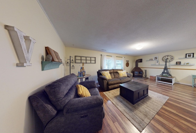 living room featuring hardwood / wood-style floors, a wood stove, and a textured ceiling