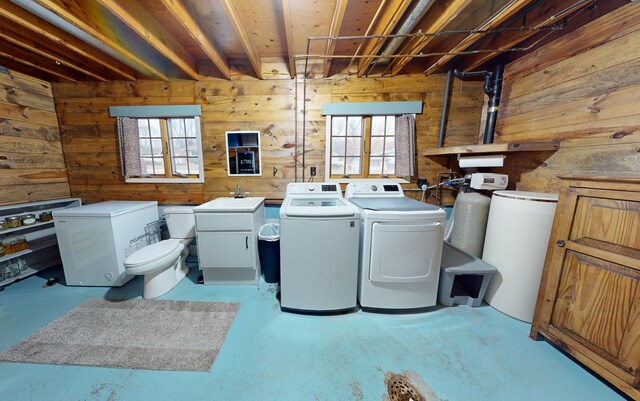 washroom with separate washer and dryer, a wealth of natural light, and wood walls