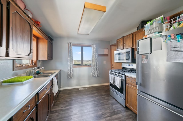 kitchen with appliances with stainless steel finishes, dark hardwood / wood-style flooring, and sink