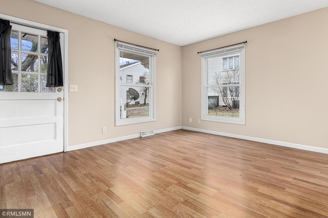 interior space featuring a textured ceiling, light hardwood / wood-style floors, and a healthy amount of sunlight