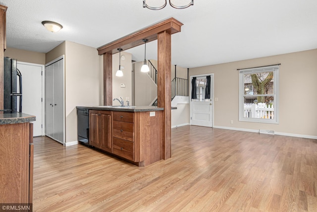 kitchen with black appliances, sink, hanging light fixtures, and light wood-type flooring