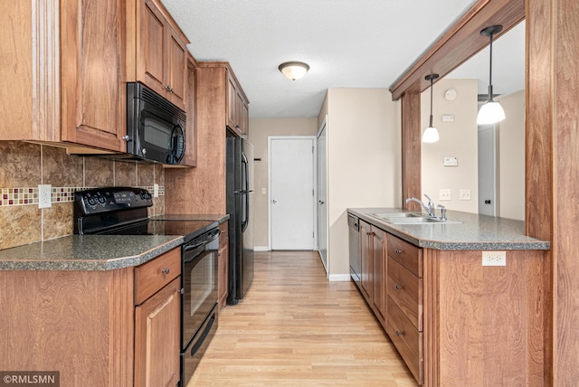 kitchen with decorative backsplash, sink, black appliances, pendant lighting, and light hardwood / wood-style flooring