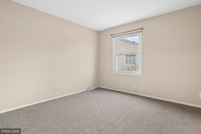 carpeted empty room featuring a textured ceiling