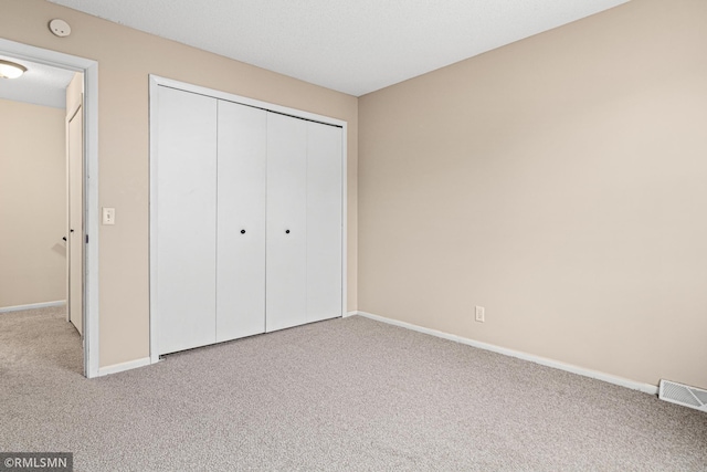 unfurnished bedroom featuring light colored carpet and a closet