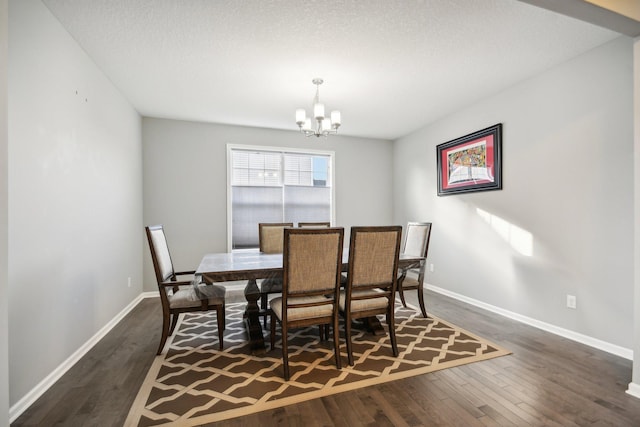 dining area featuring dark wood-type flooring, a textured ceiling, and an inviting chandelier