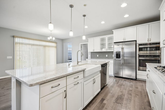 kitchen featuring stainless steel appliances, dark hardwood / wood-style floors, hanging light fixtures, sink, and a kitchen island with sink