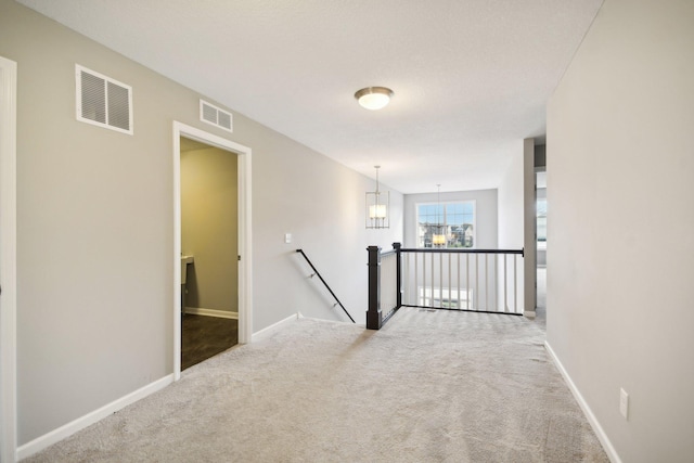 hallway with light carpet and a notable chandelier