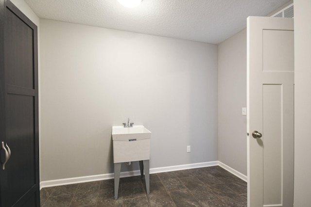 clothes washing area featuring a textured ceiling