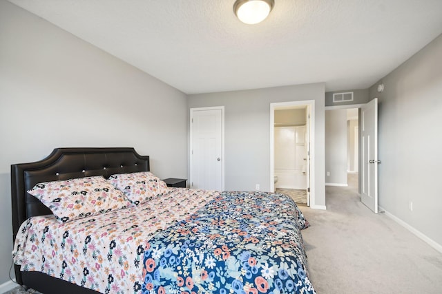 carpeted bedroom featuring a textured ceiling and connected bathroom