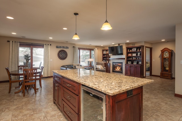 kitchen with decorative light fixtures, a kitchen island, light stone counters, and beverage cooler