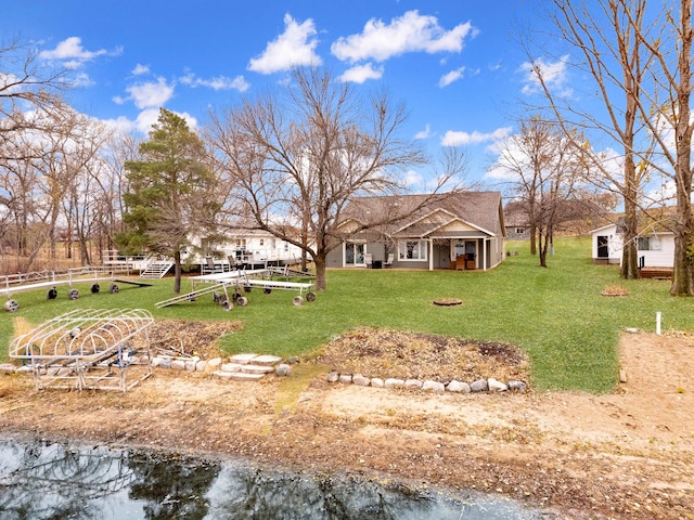 rear view of property featuring a water view and a lawn