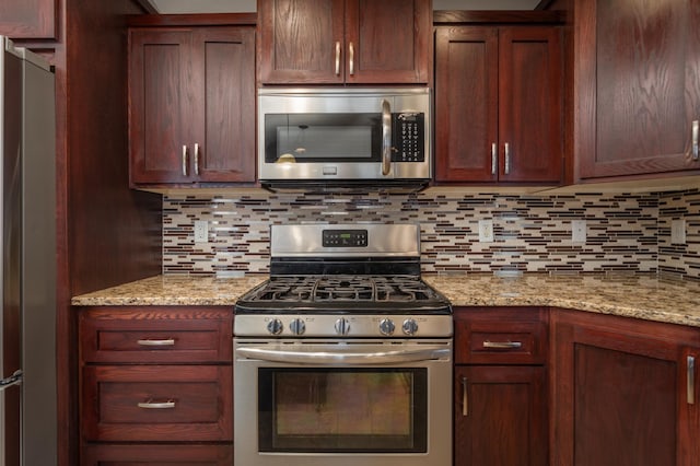 kitchen with backsplash, light stone counters, and stainless steel appliances