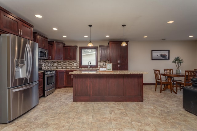 kitchen with light stone counters, stainless steel appliances, sink, pendant lighting, and a kitchen island