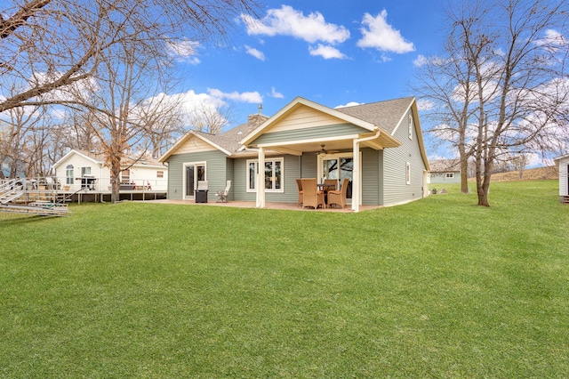 back of property with ceiling fan, a yard, and a patio